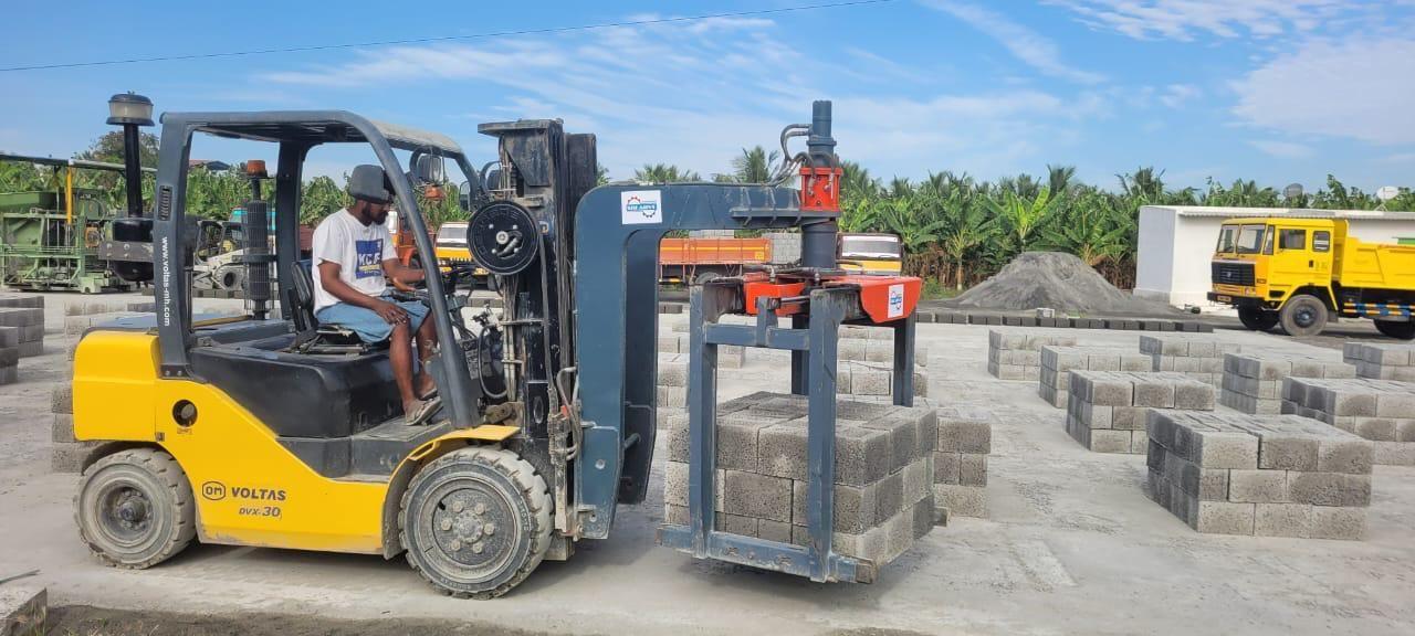 Forklift with brick grabber loading a stack of blocks