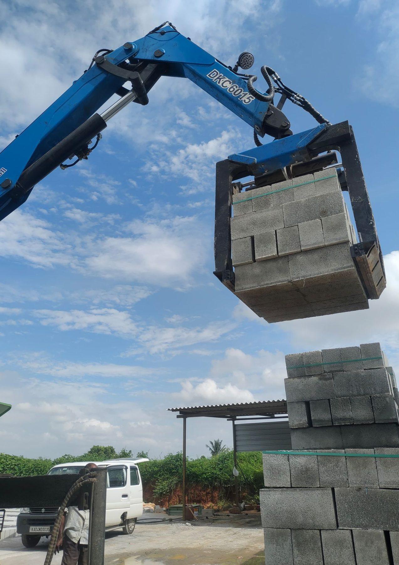 Crane brick grabber lifting a stack of hollow blocks