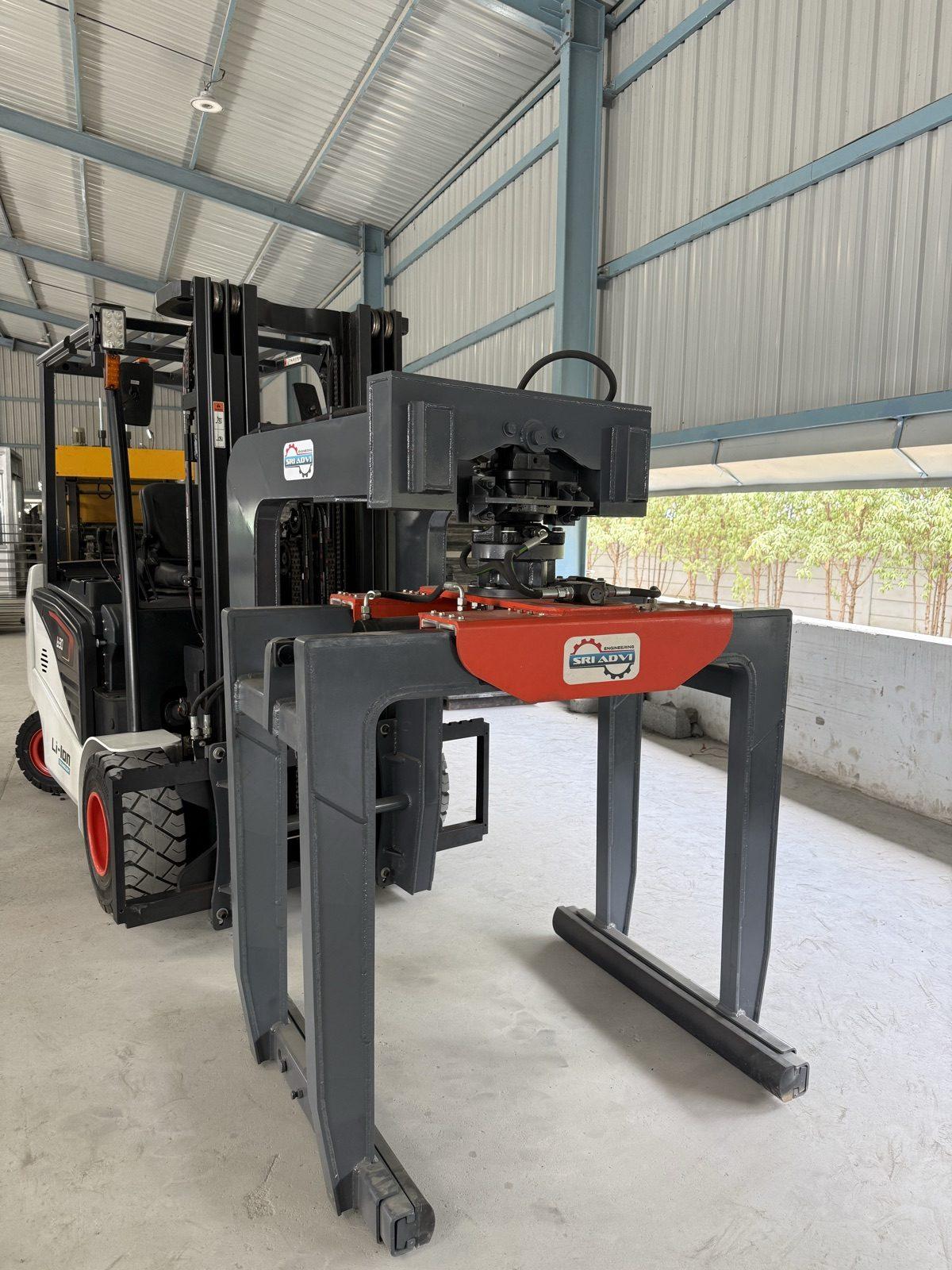 SAE 02 high-lift brick grabber with its orange rotator, on a forklift in the workshop